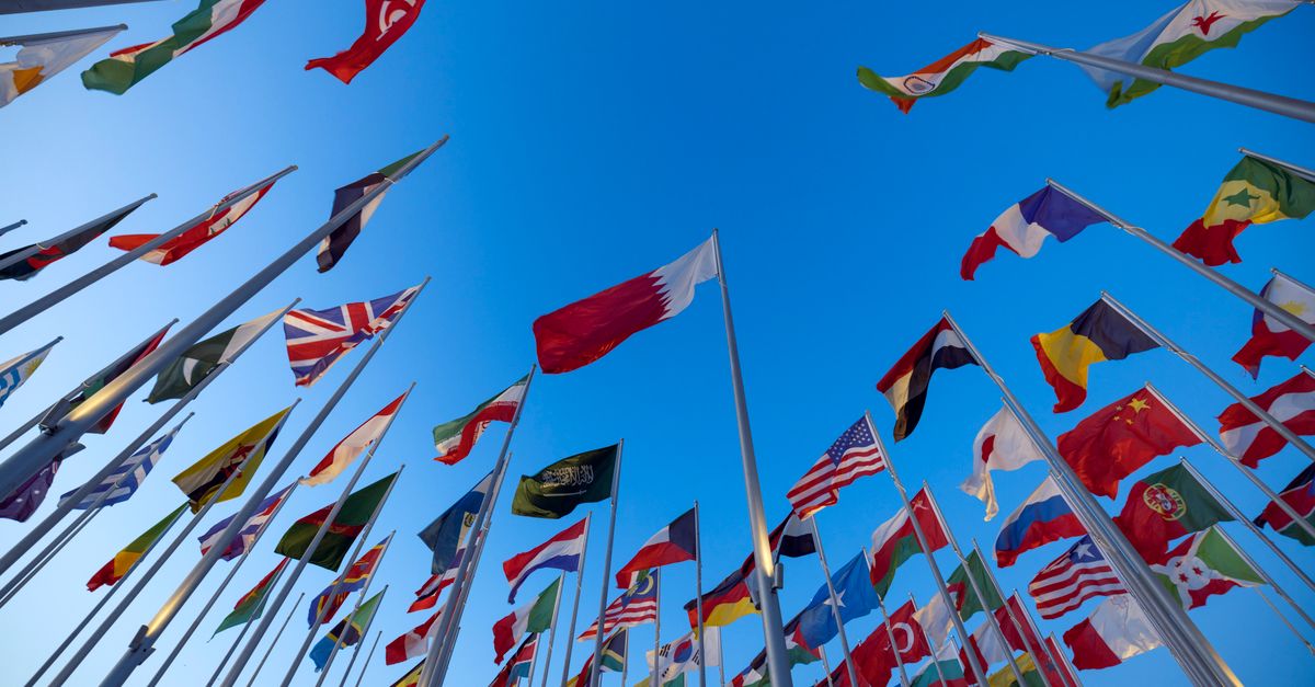 International flags waving against a clear blue sky in Doha, Qatar, symbolizing unity and diversity.
